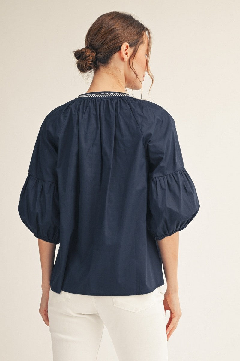 Front view of a white cotton top with balloon sleeves, notched V-neck, and front button closure.