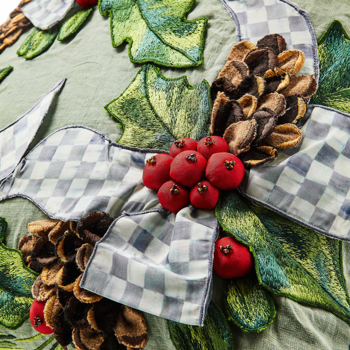 Farmhouse holly holiday throw pillow with green leaf embroidery on a natural linen background.