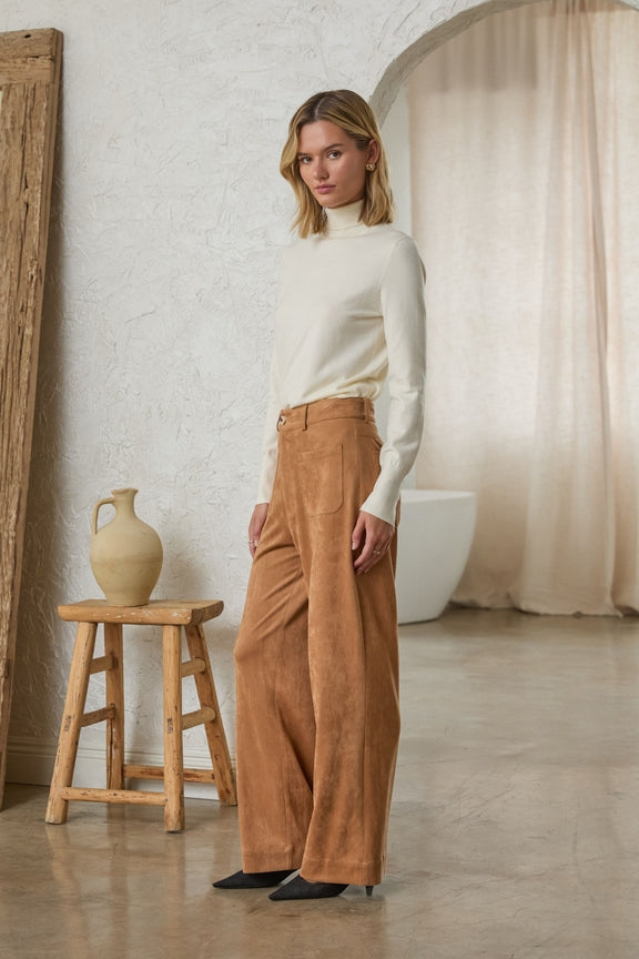 Model wearing Lucy Faux Suede Wide Leg Pants in tan with a white turtleneck and black heels.