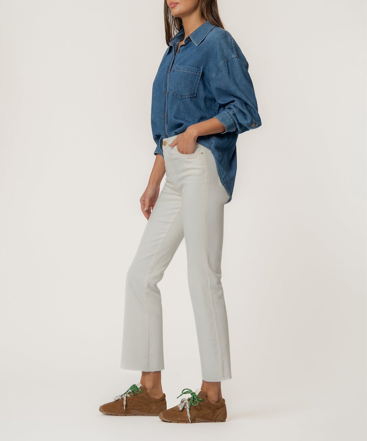 Woman wearing Kelsey high-rise ankle flare jeans in white with a raw hem and a denim shirt.