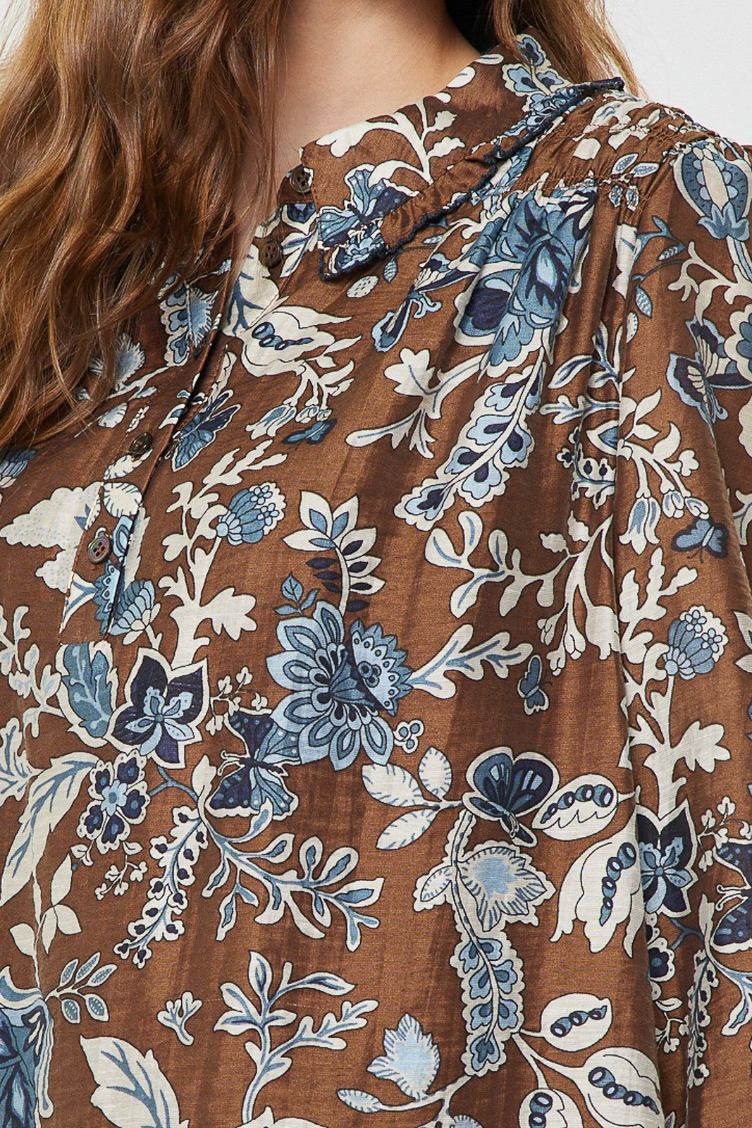 Sheer floral paisley blouse with shirt collar, ruffled detail, half placket buttons, and smocked back in Tencel blend.