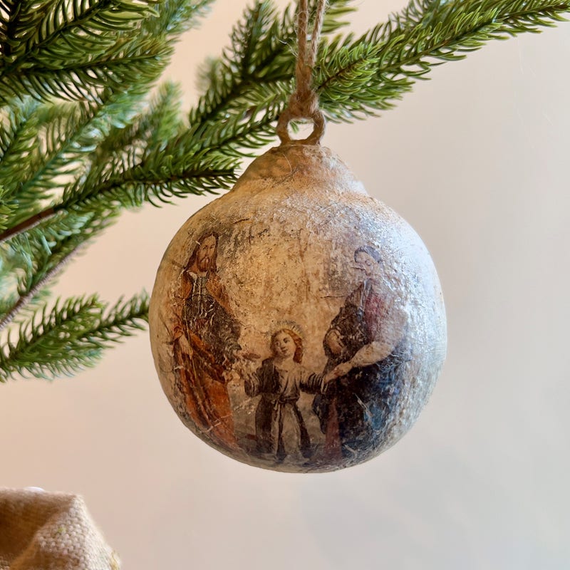 Small metal Holy Family ornament featuring a standing figure group in gold finish with detailed robes and halo accents.