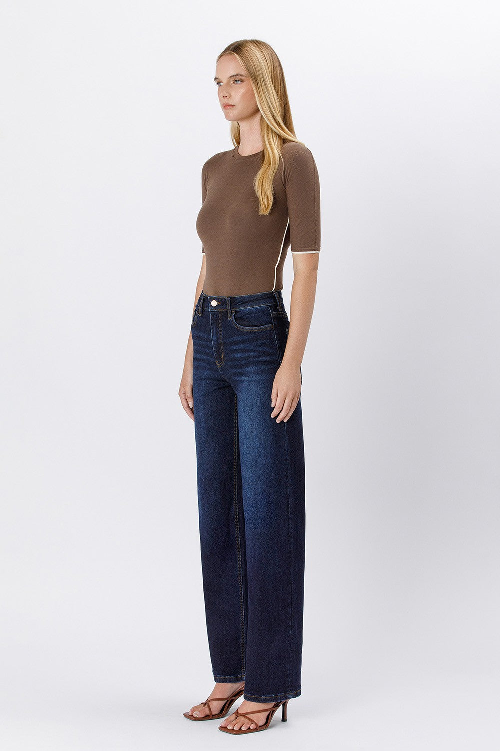 Woman wearing Trixie 90’s vintage super high rise dark wash loose jeans and a brown top.