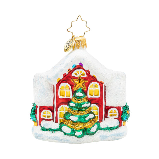 Glass Christmas ornament of a red house with a snow-covered roof and a decorated tree in front.