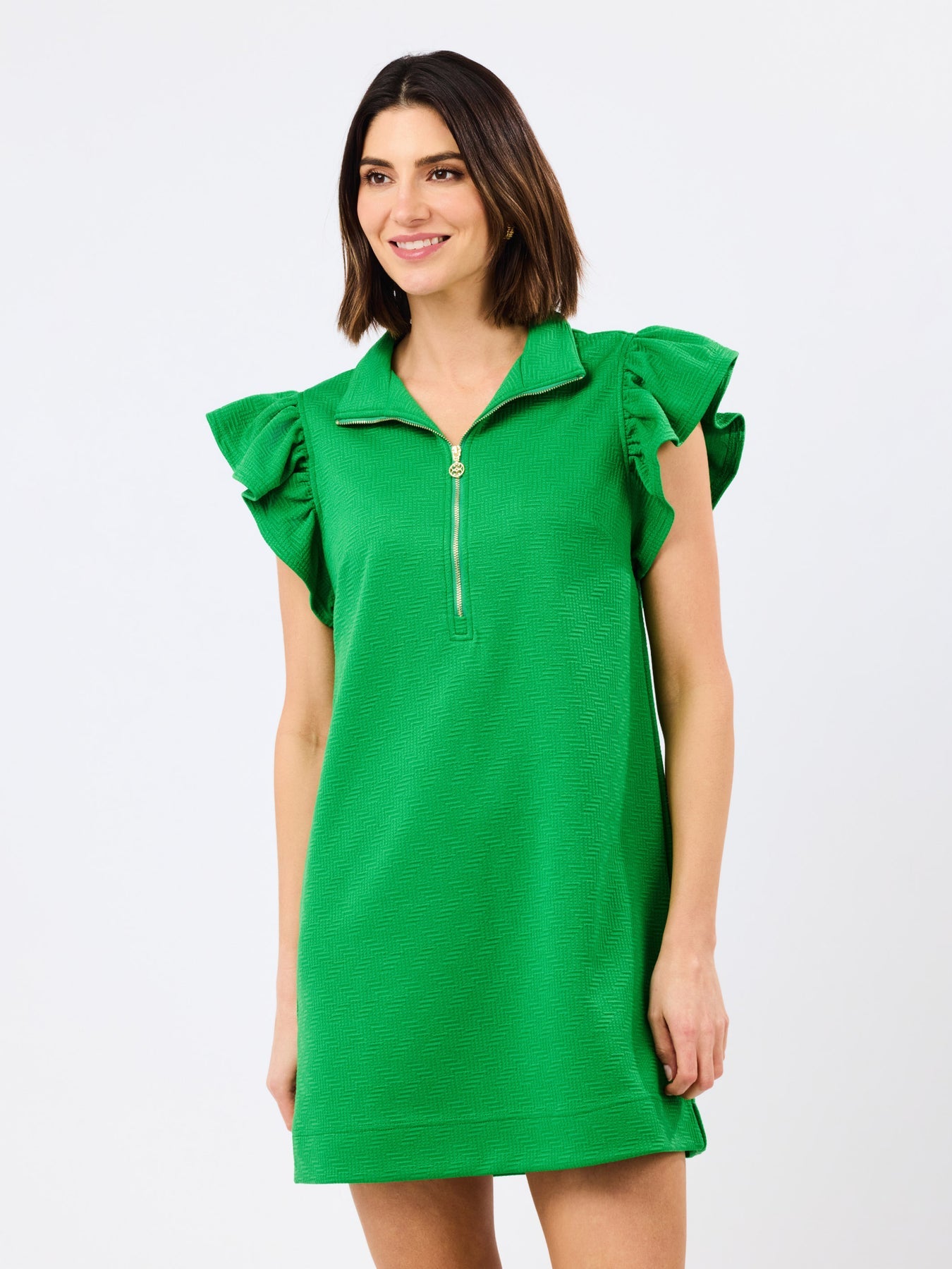 Woman wearing the green Paige Dress with flutter sleeves, a pop-collar, and a gold front zipper.