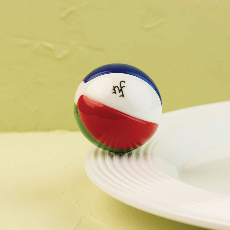 Hand-painted colorful beach ball decorative mini on the edge of a white ceramic plate.