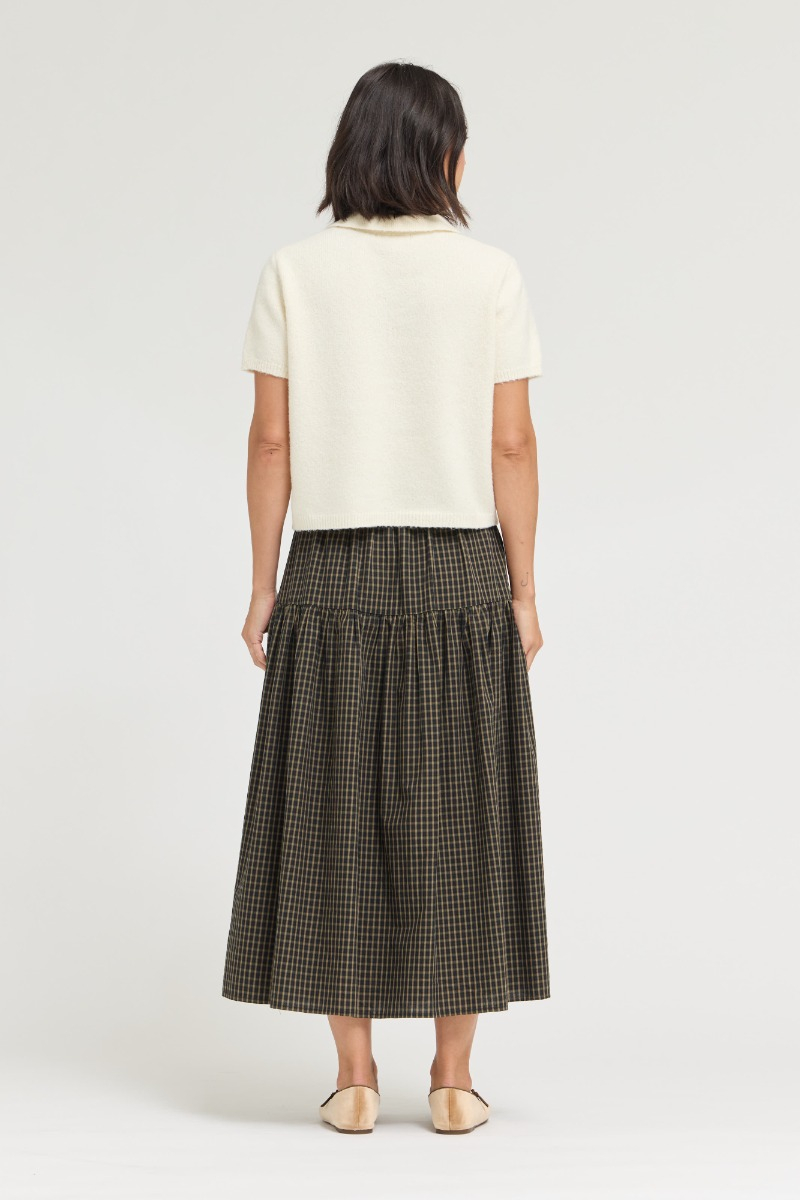 Back view of a woman wearing the ivory Marian Half Placket Short Sleeve Knit and a plaid skirt.
