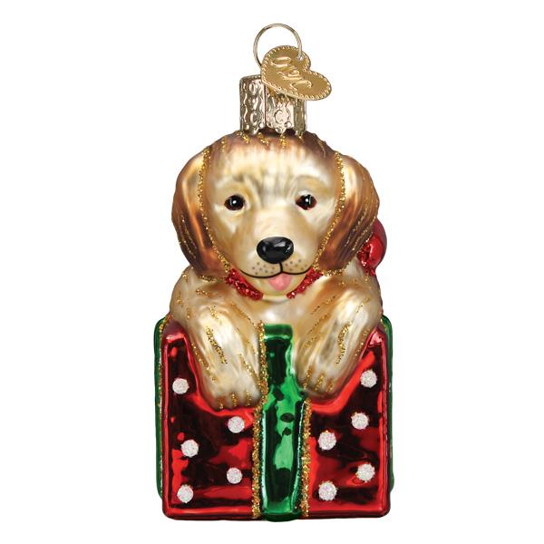 Golden puppy glass ornament sitting inside a red polka dot gift box with a green ribbon.