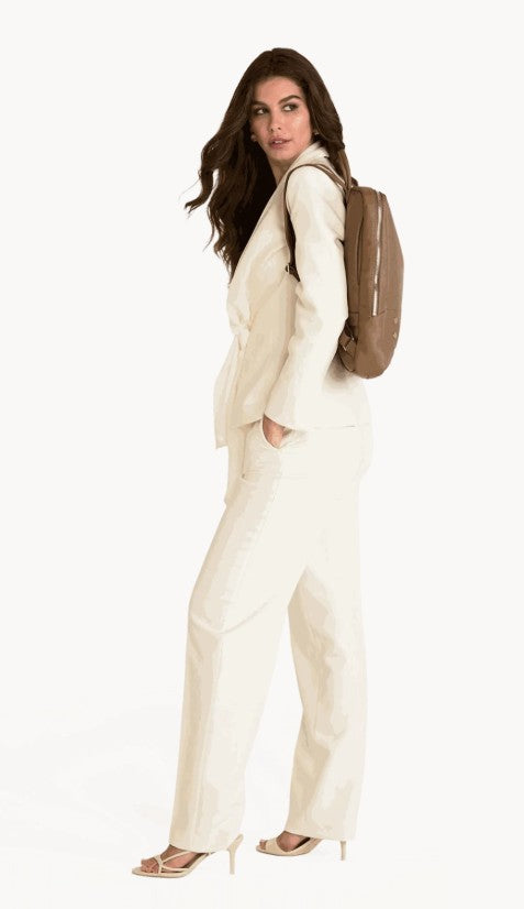A woman wearing a white suit carries the Hammitt Hunter Large Backpack in Dune leather.