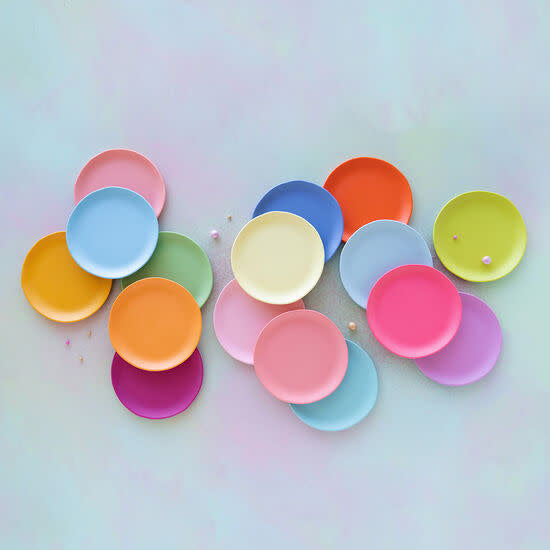 A collection of colorful, round melamine dinner plates in various bright shades.