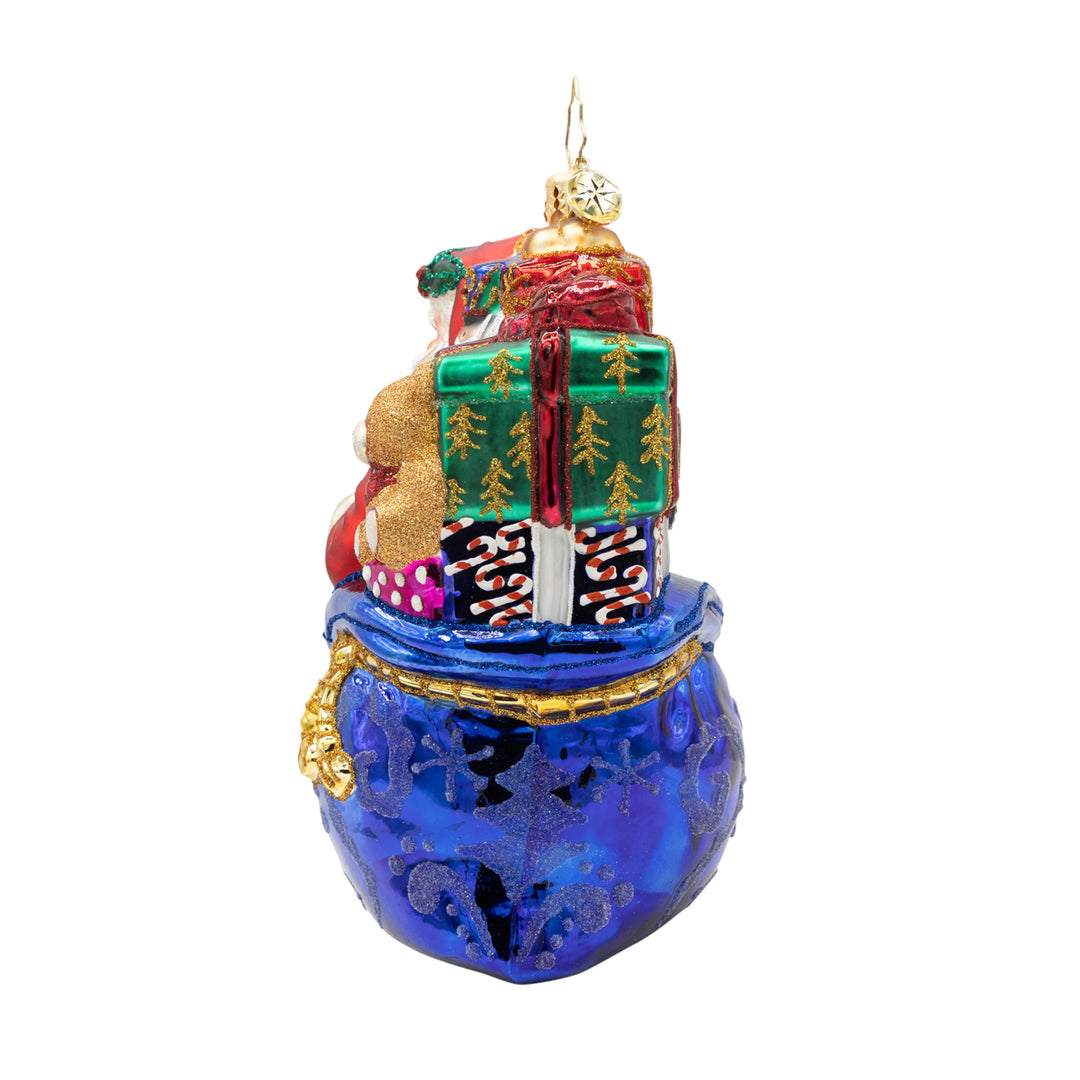Back view of a glass Santa ornament showing a blue sack filled with colorful glittery gifts.