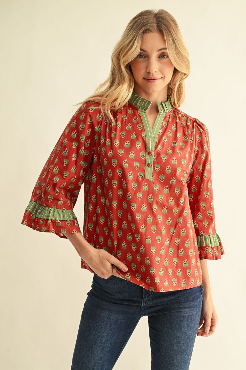 Woman wearing a red floral Jane top with green striped ruffle bell sleeves and a notched V-neck.