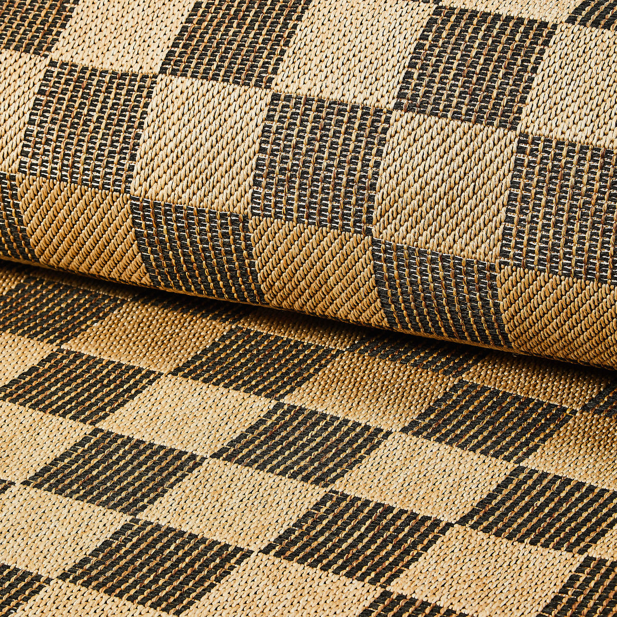 Close-up of a black and tan checkered indoor/outdoor rug with a woven polypropylene texture.