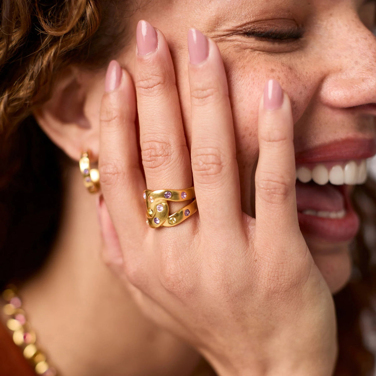 Rainbow infinity ring with multicolored CZ stones set in a gold-plated band.
