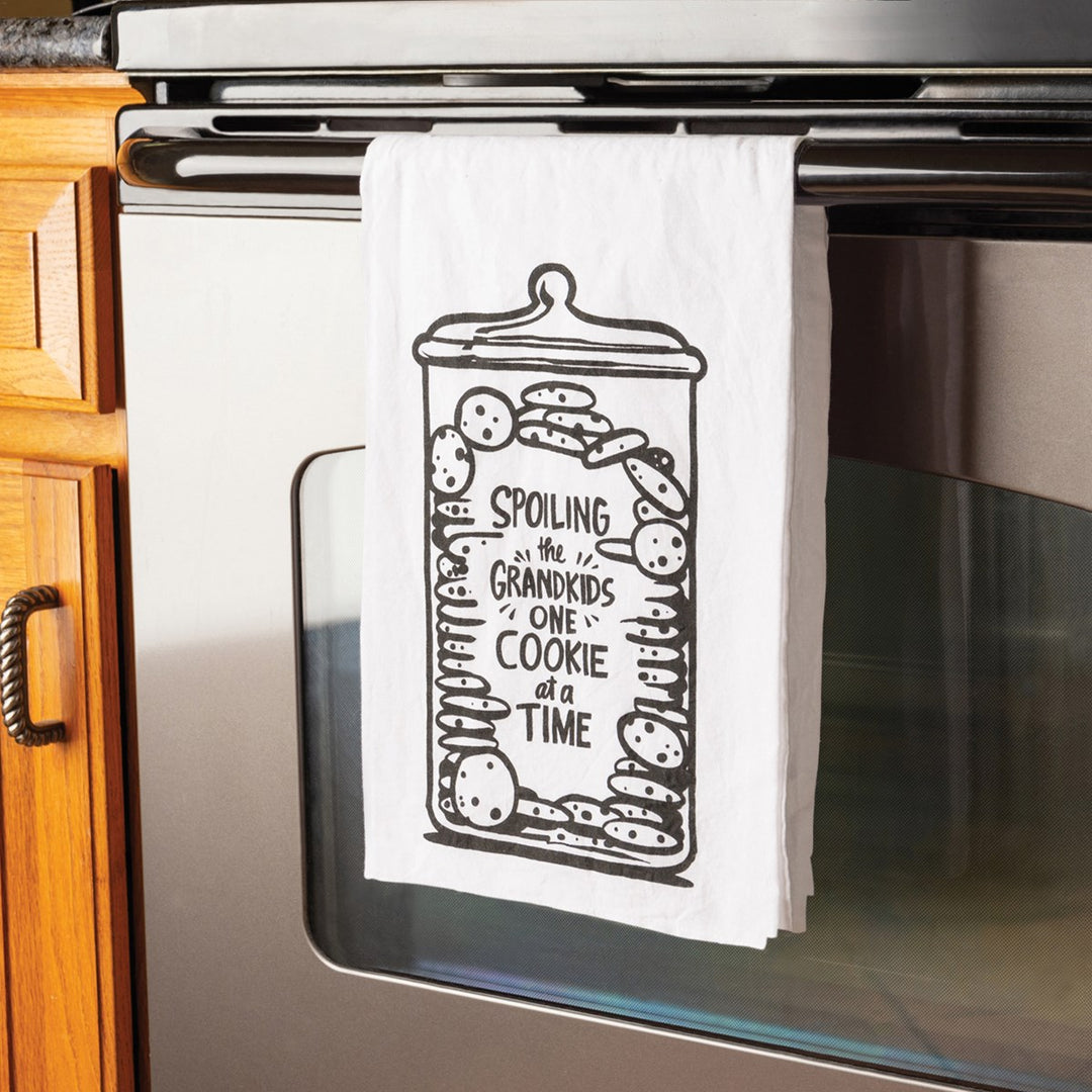 White cotton kitchen towel with a black graphic of a cookie jar filled with cookies and the text "Spoiling the grandkids one cookie at a time."