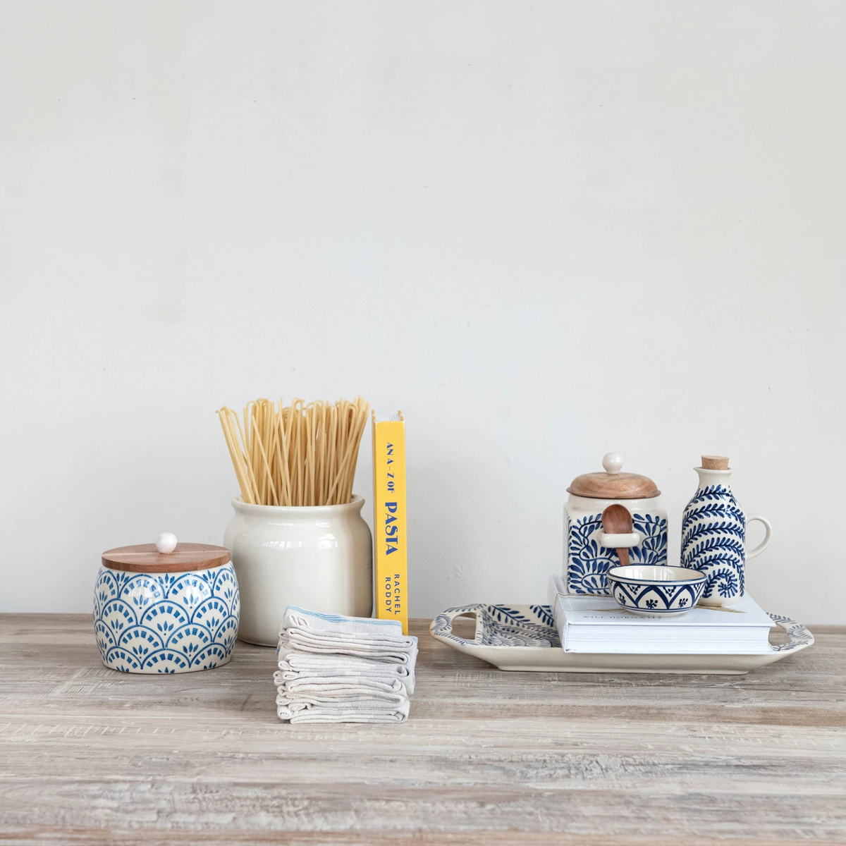 Hand-painted blue and white patterned stoneware bowl on a stack of books with kitchen accessories.