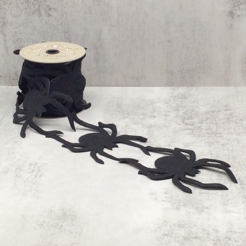 4-inch wide black spider garland ribbon unspooled on a light grey surface.