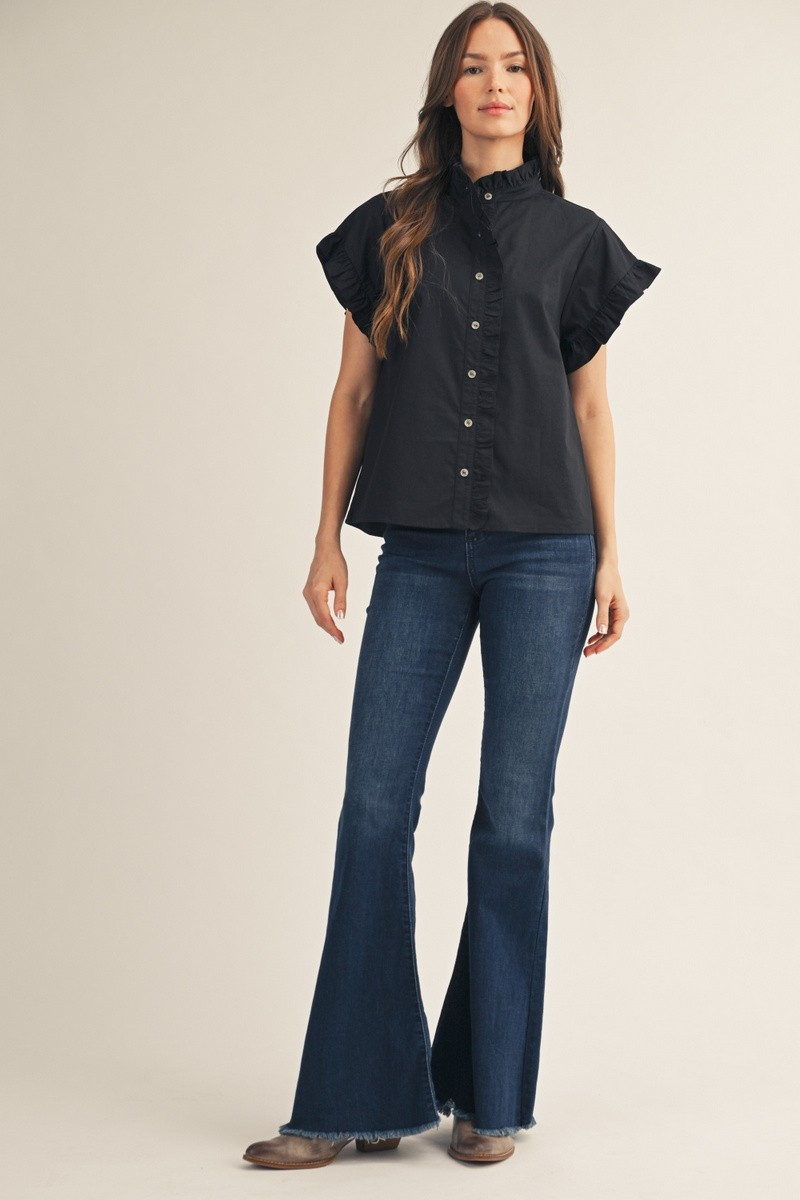 Woman wearing the Elise black short-sleeve top with ruffled collar and sleeves and flared jeans.