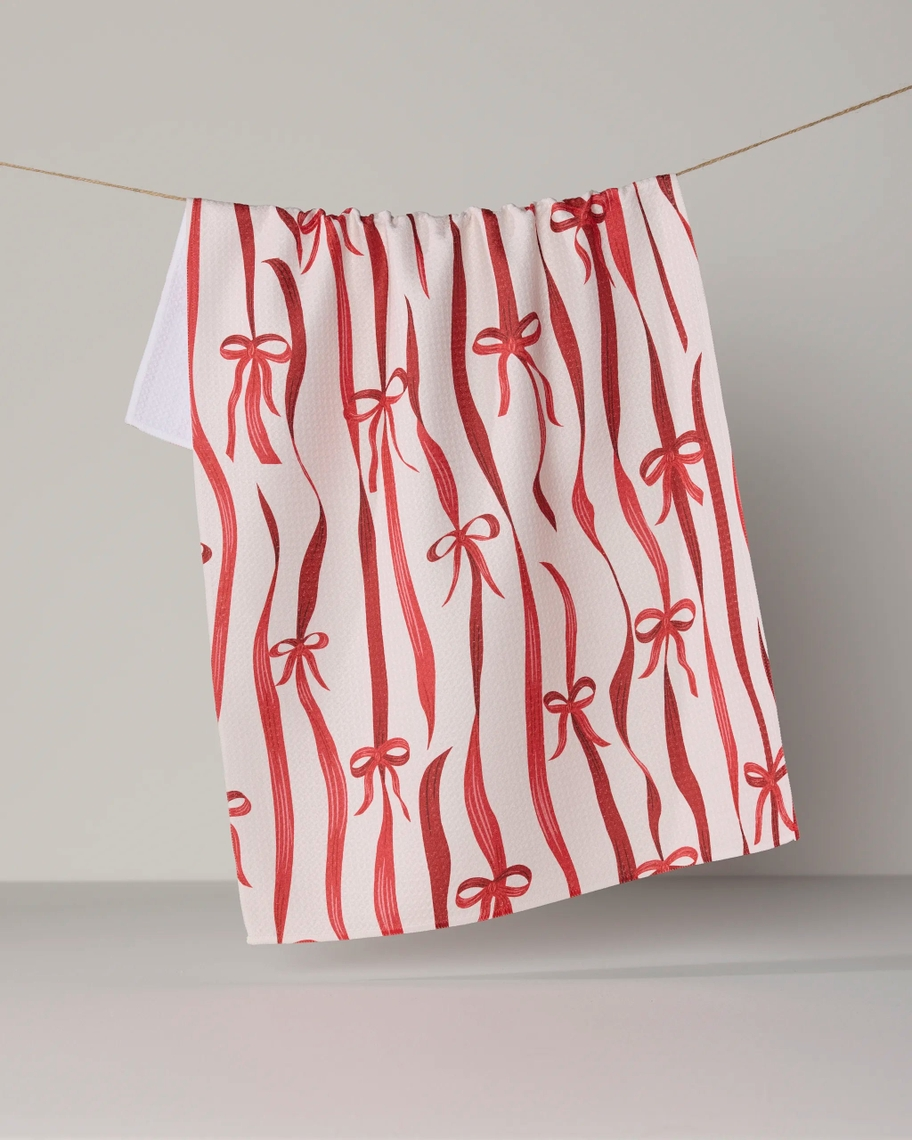 Everyday tea towel with a red ribbon and bow pattern hanging on a clothesline.