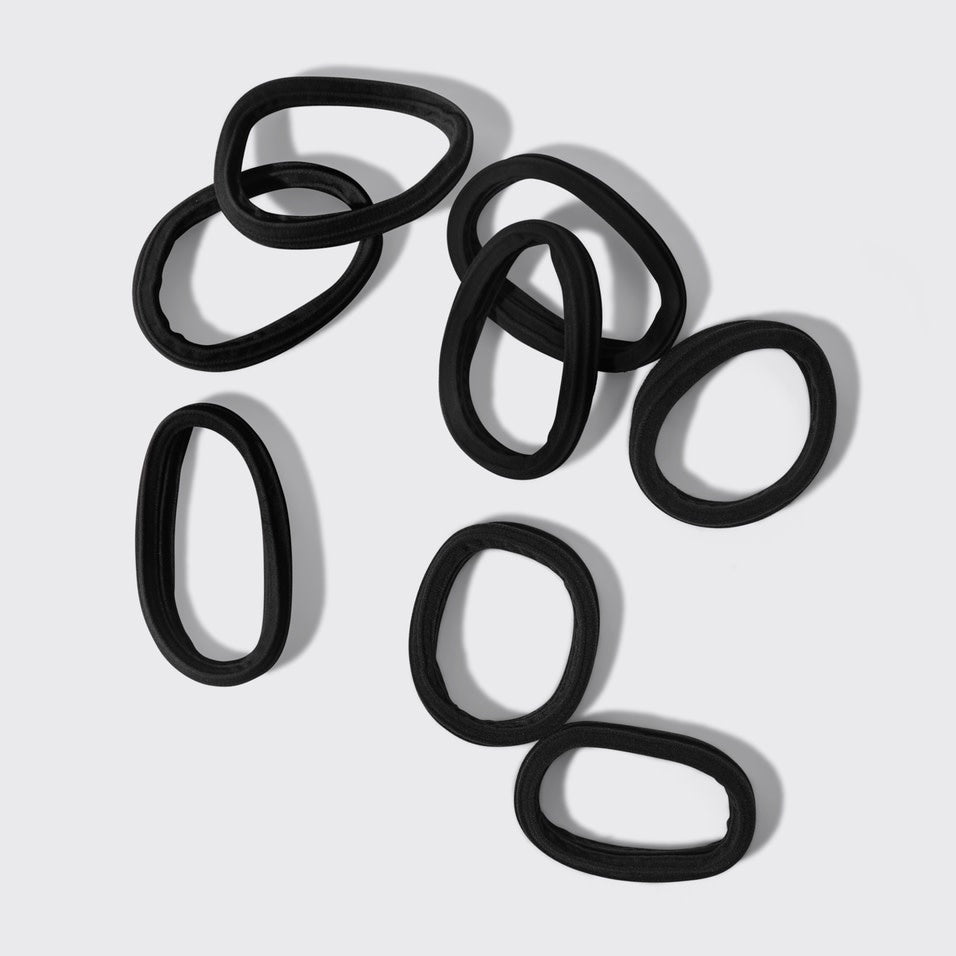Packaging showing a set of eight black recycled seamless hair elastics.