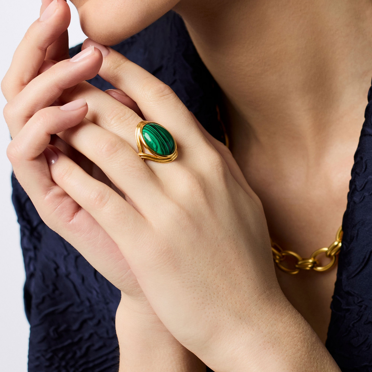 A person wearing the Essex Statement Ring, featuring a large oval green malachite stone in gold.