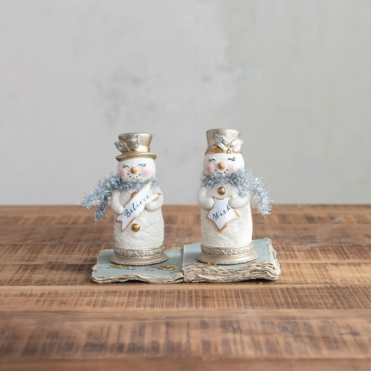 Resin snowman figurine with a red scarf holding a festive sign