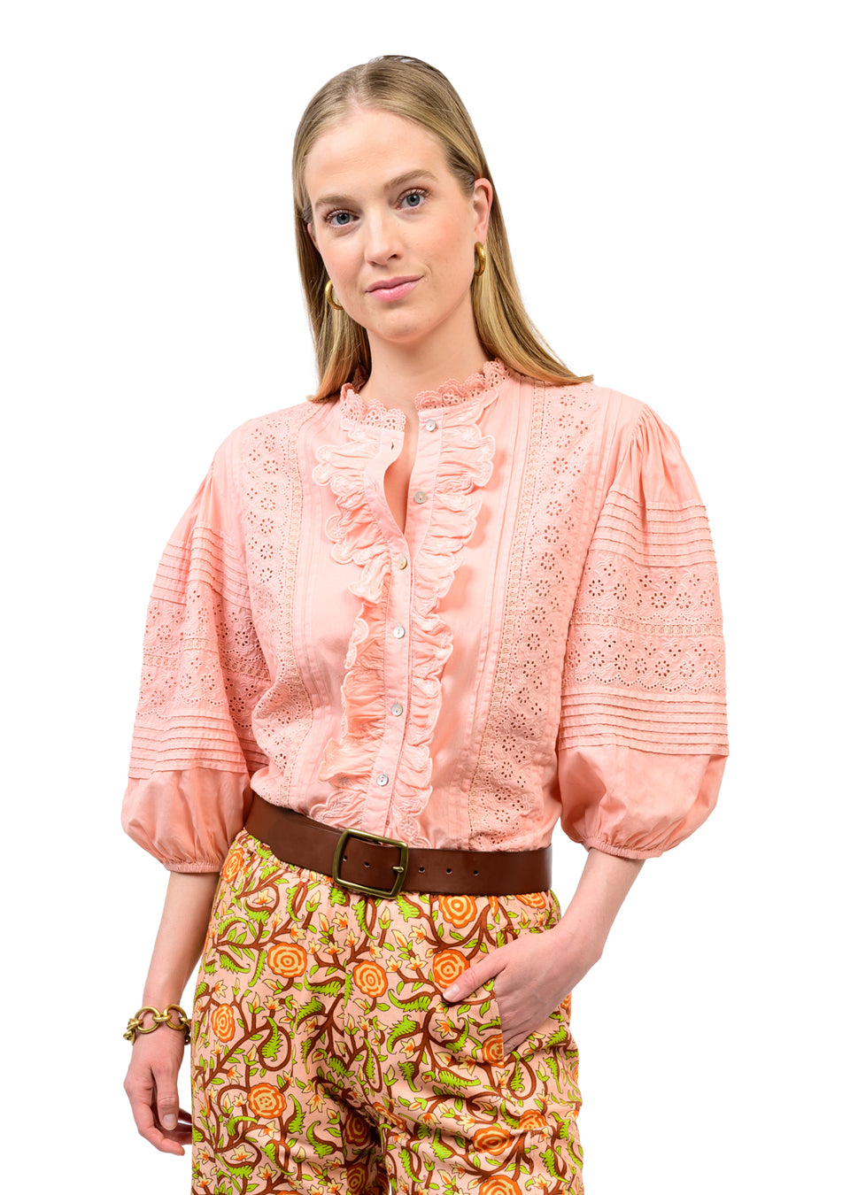Woman wearing the Irene Eyelet Embroidered Top in peach with ruffles and puff sleeves.
