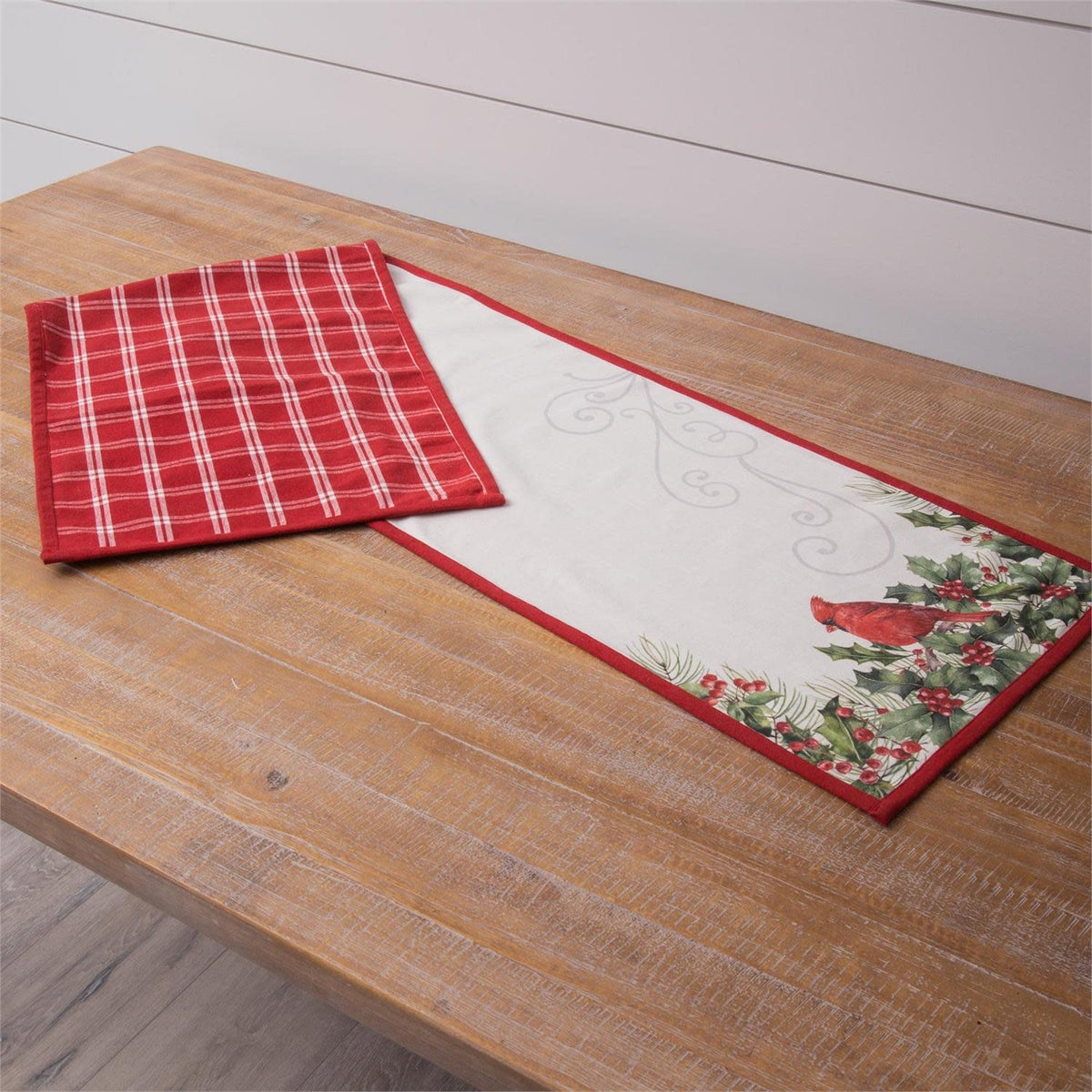 Reversible cotton table runner with cardinal and holly print on one side.