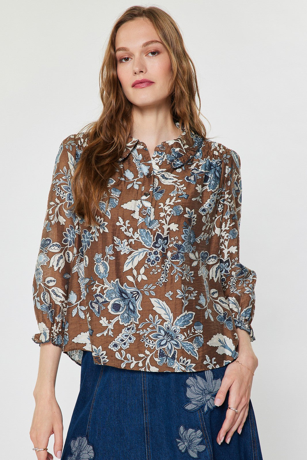 Sheer floral paisley blouse with shirt collar, half placket buttons, ruffled detail, and smocked back in Tencel blend.