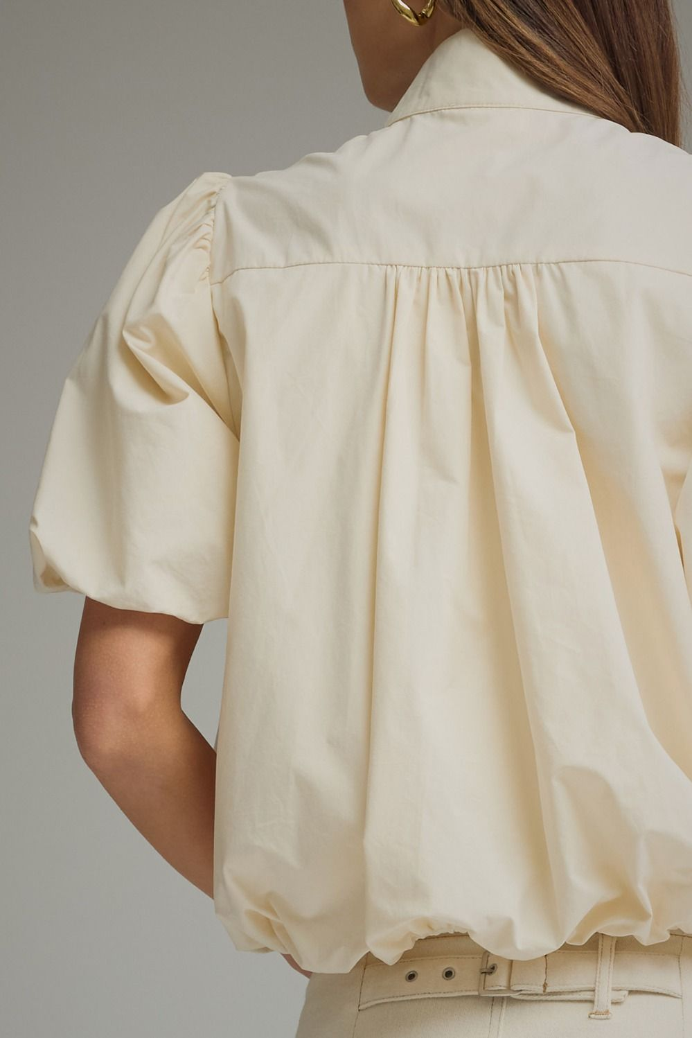 Back view of a cream Jacky short puff sleeve top with a bubble hem and gathered yoke detail.