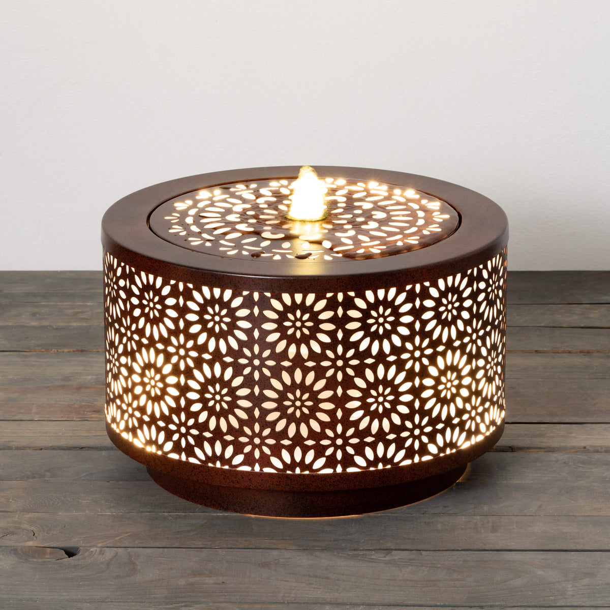 Brown metal round fountain with pierced copper detailing holding two liters.
