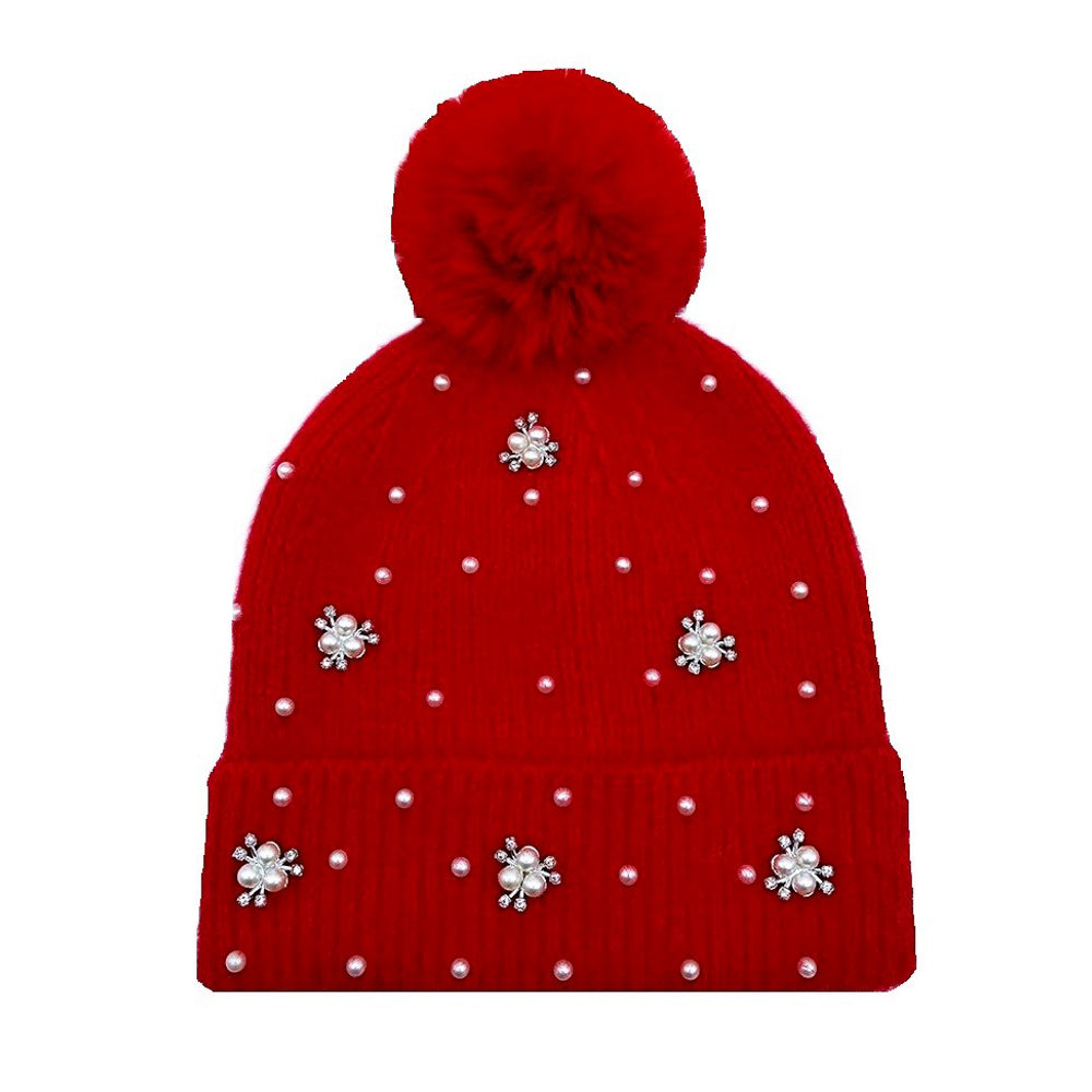 Black knit beanie with a fluffy pom pom top, pearl studs along the brim, and ribbed texture.