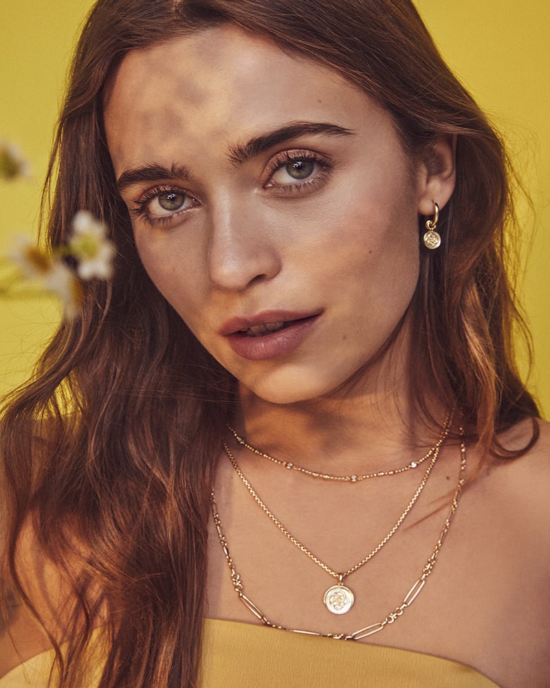 Woman wearing a gold Medallion Coin Triple Strand Necklace with three layered chains.
