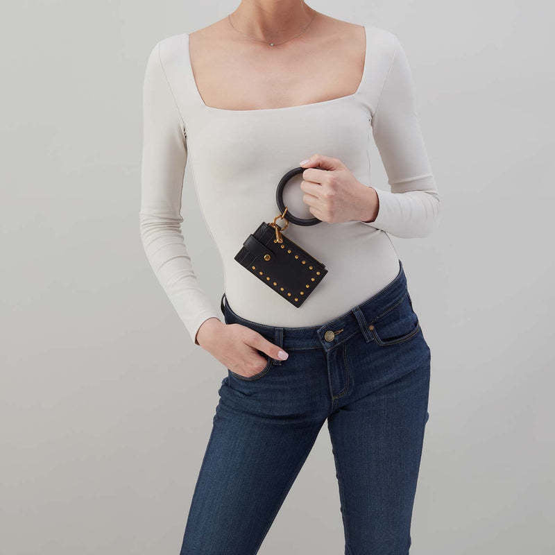 Black leather ring wristlet with brushed brass hardware and zip pocket.