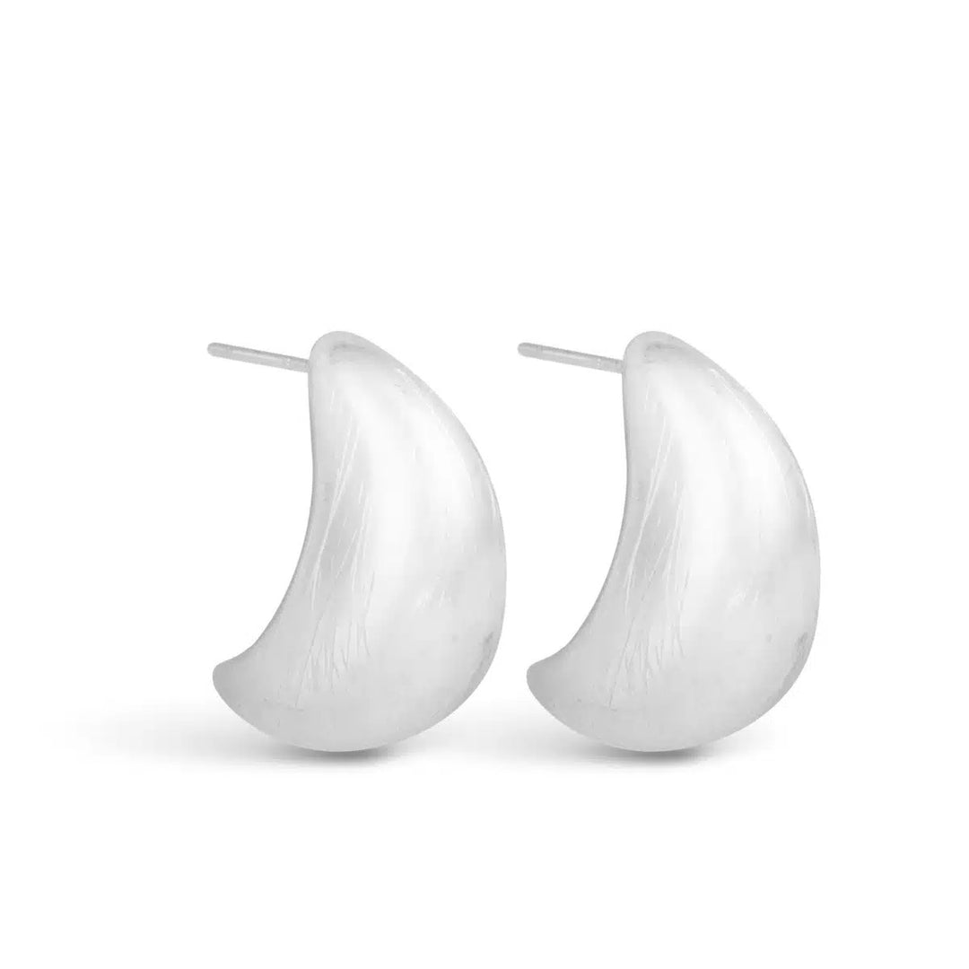 A pair of Lee Matte Full Huggie Silver Earrings with a smooth, crescent-shaped design.