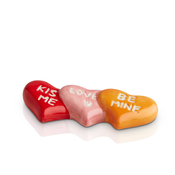 Three connected ceramic conversation hearts in red, pink, and orange with romantic white text.