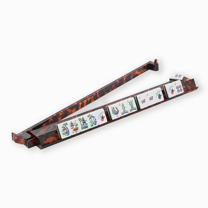 Tortoise shell acrylic mahjong rack and pusher with tiles on a white background.