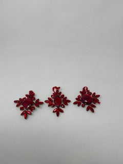 Metal snowflake ornament with red jewels on a white background