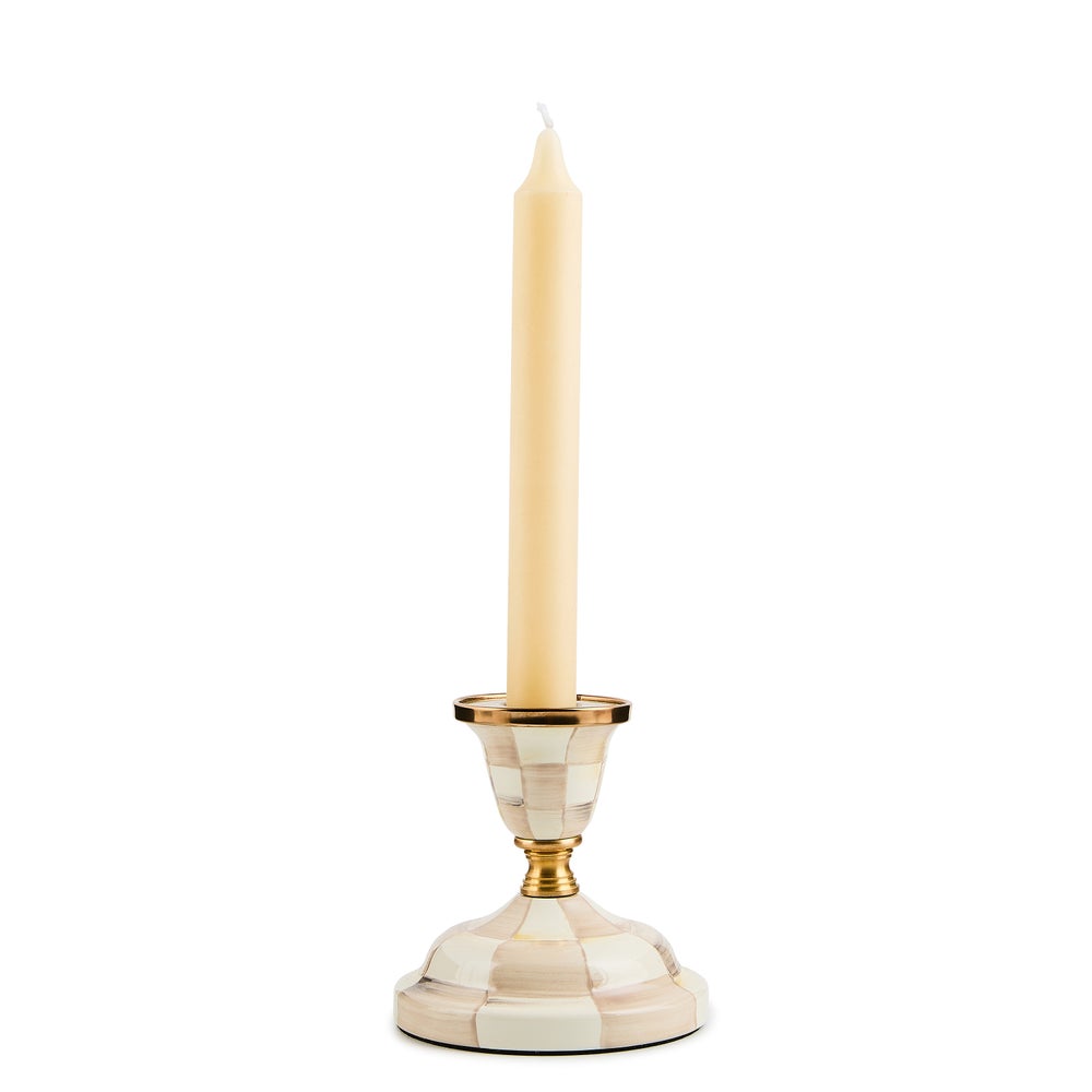 Mackenzie Childs Mocha Check short candlestick with brass accents and a cream taper candle.