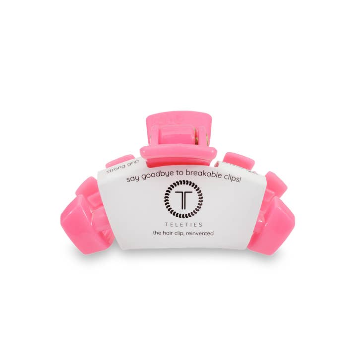 Tiny pink Teleties hair clip with a white label featuring the brand logo and "strong grip" text.