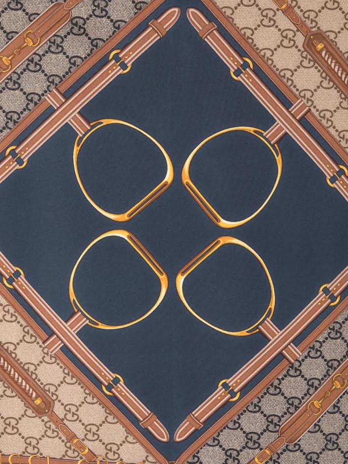 Silk scarf with a navy center, gold stirrup motifs, and brown GG monogram border with belt details.