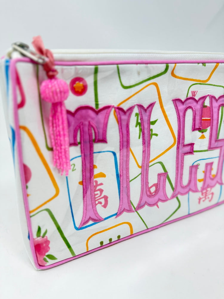Tiana Design Mahjong Cosmetic Bag with pink embroidered 'TILES' text and a pink tassel zipper pull.
