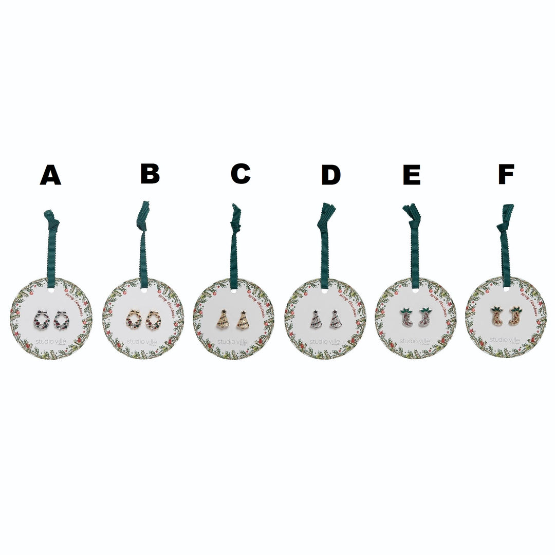 Six pairs of festive Christmas earrings on round cards: bows, trees, and stockings in gold, silver, and red.