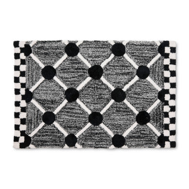 Handmade cotton bath rug with a lattice and dot geometric pattern in neutral tones.