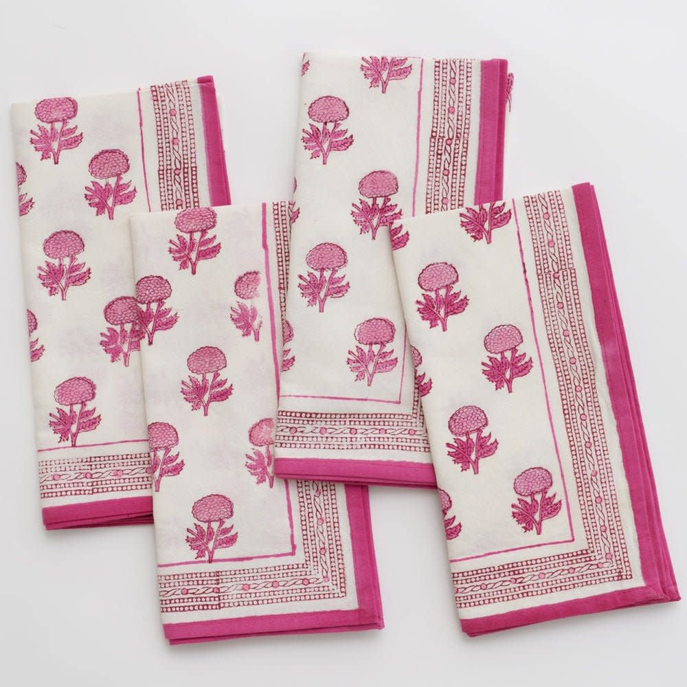 Set of four square white cotton napkins with a bright pink rose wine motif pattern.