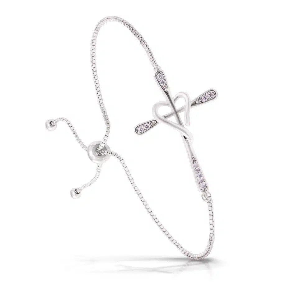 Silver pull-cord bracelet featuring a pave-set cross entwined with a polished heart charm.