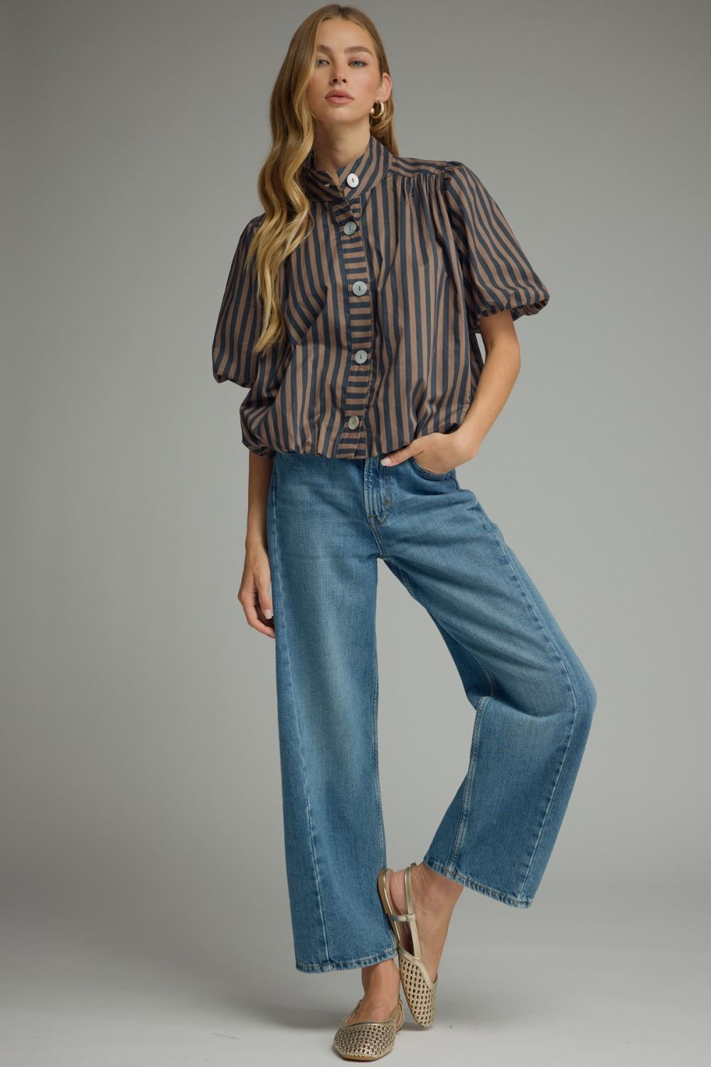 Woman wearing a Camila Stripe Short Puff Sleeve Top in brown and navy with wide-leg blue jeans.