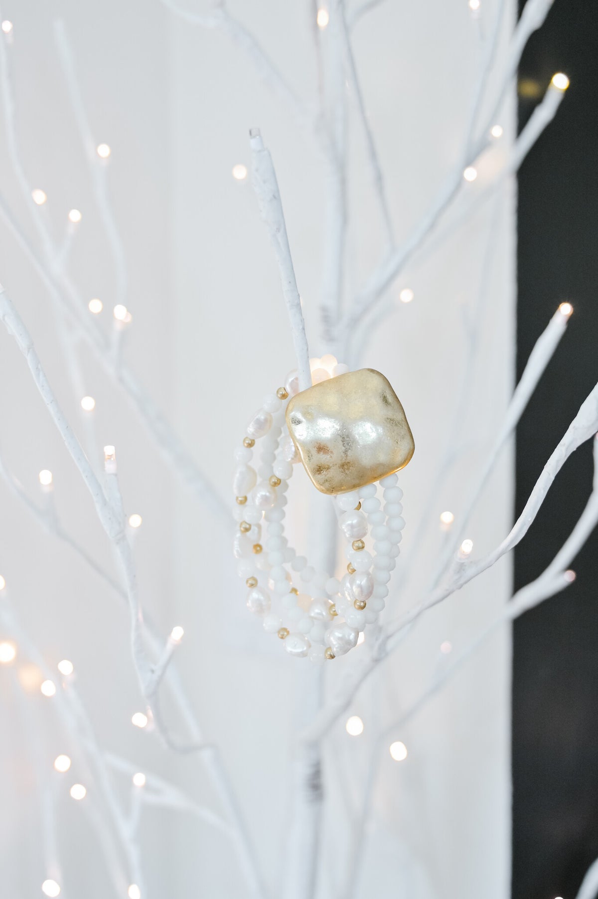 Stretch bracelet with white beads on a gold plate chain