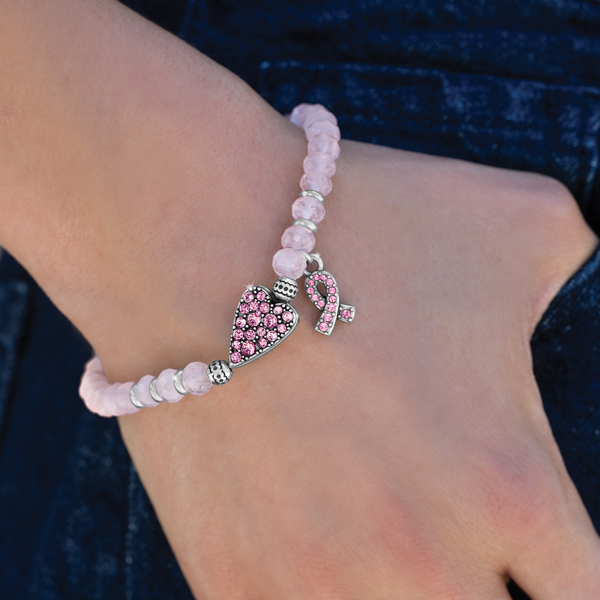 Power Of Pink 2026 stretch bracelet with pink beads, silver heart, and ribbon charms on a wrist.