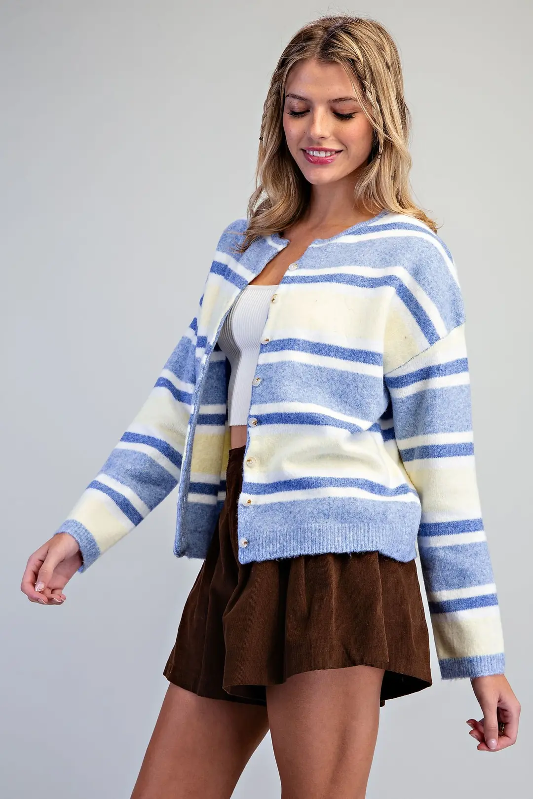 Woman wearing a blue and white horizontal striped button-front cardigan with a crew neckline.